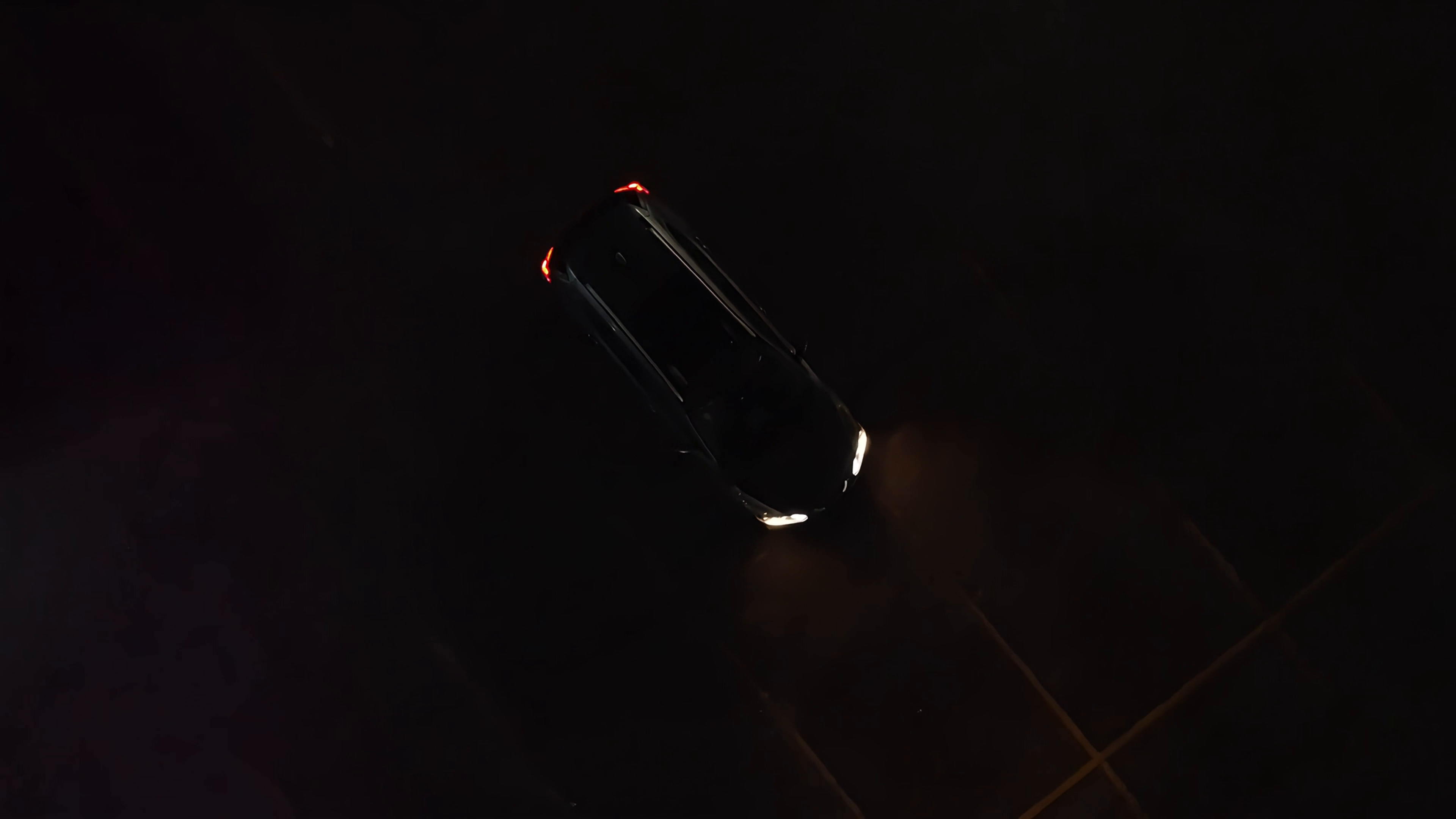 A car at night, seen from above, headlights on