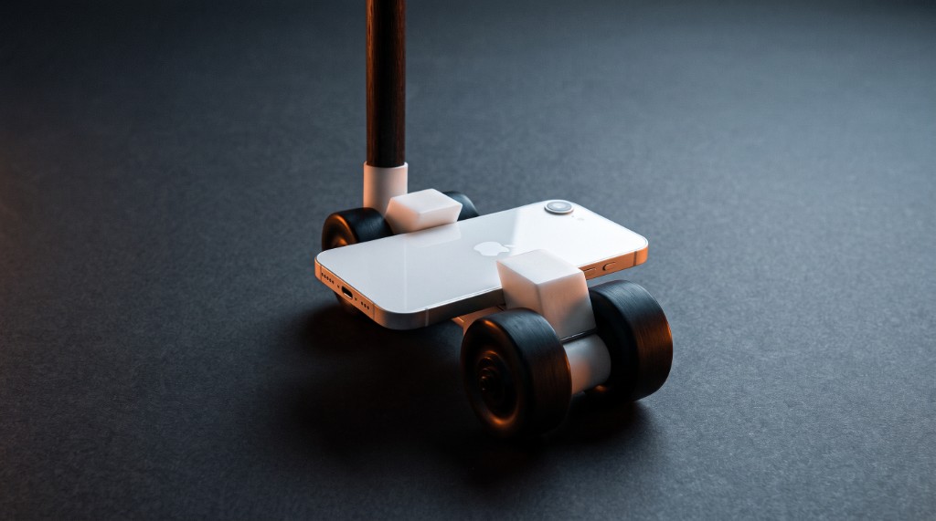 Close-up of the wheeled head: four wheels carrying a phone, with a hardwood pole rising from it